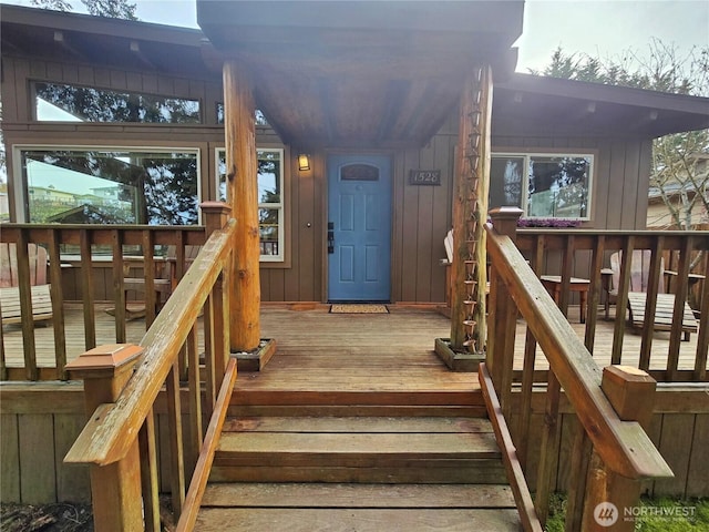 view of exterior entry featuring board and batten siding and a deck