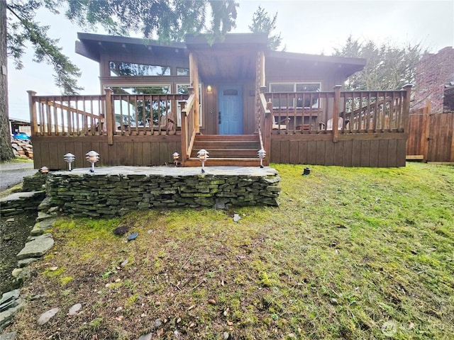 rear view of house with a yard, a deck, and fence