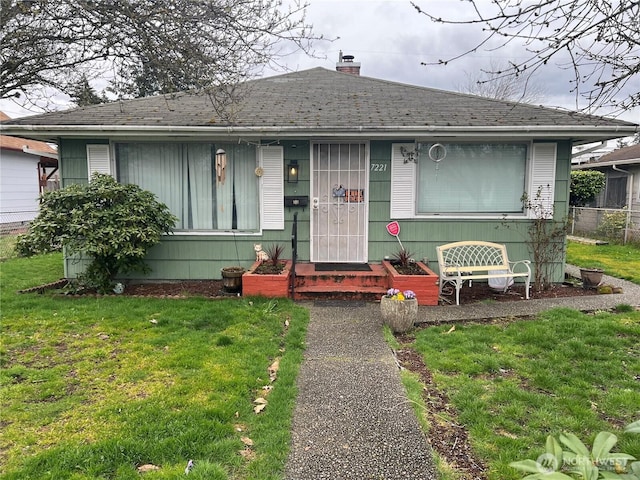 view of front of home featuring a chimney, a front lawn, and roof with shingles