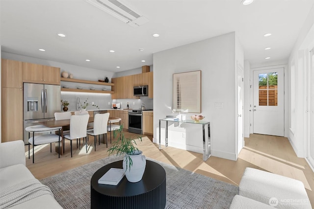 living room with recessed lighting, light wood-type flooring, and baseboards