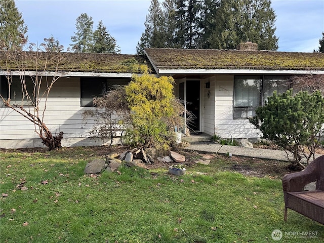 single story home with a chimney and a front yard