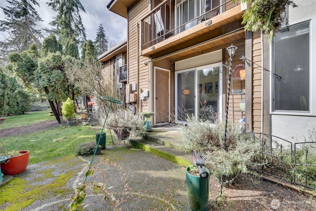 doorway to property with a balcony and a lawn