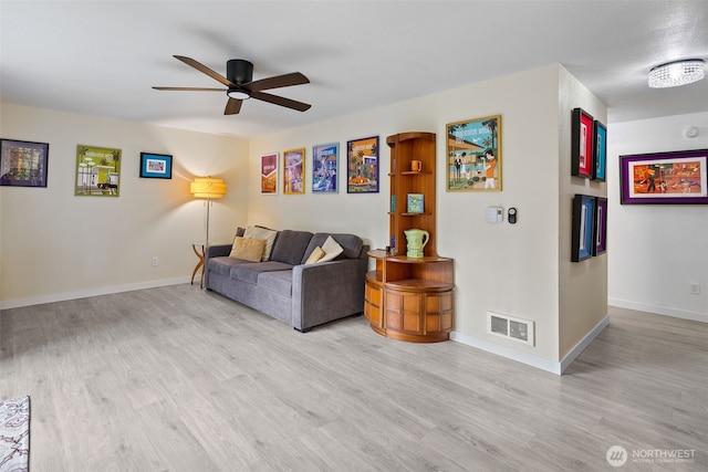 living area featuring visible vents, baseboards, wood finished floors, and a ceiling fan