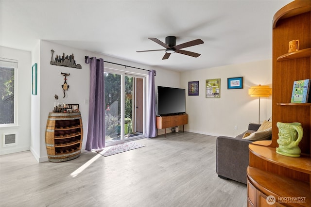 living room with visible vents, baseboards, light wood-style floors, and a ceiling fan