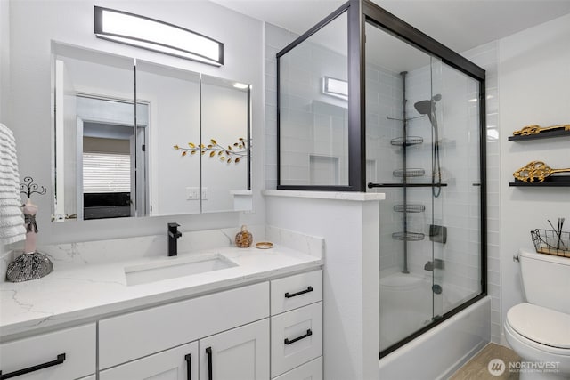 bathroom with vanity, toilet, and shower / bath combination with glass door