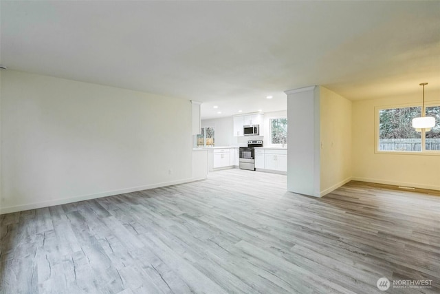 unfurnished living room with recessed lighting, light wood-style flooring, and baseboards