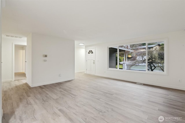 unfurnished living room featuring light wood finished floors, visible vents, and baseboards