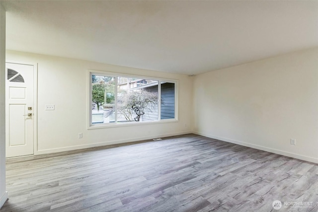 spare room with baseboards and wood finished floors