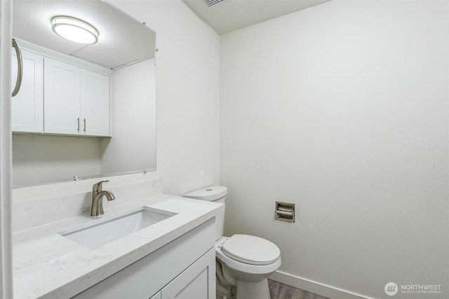 bathroom with vanity, toilet, wood finished floors, and baseboards