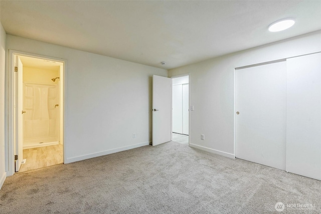 unfurnished bedroom featuring a closet, baseboards, ensuite bath, and carpet