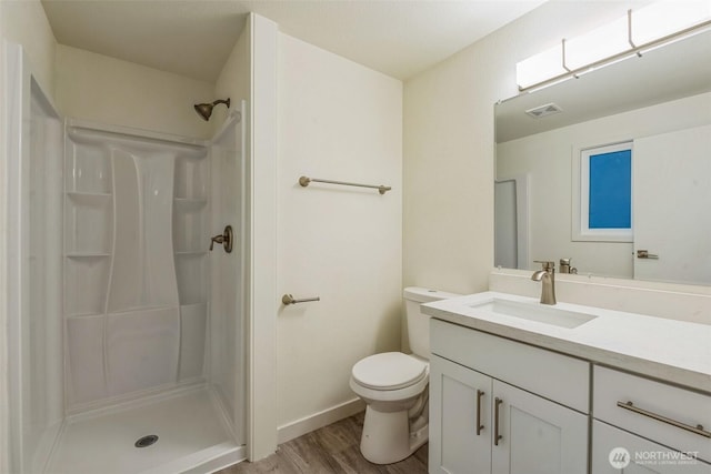 bathroom featuring visible vents, a shower stall, toilet, wood finished floors, and vanity