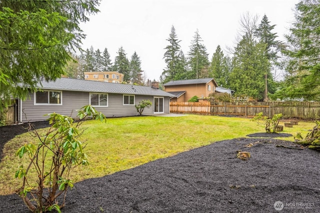 back of house featuring a lawn, metal roof, a standing seam roof, and fence