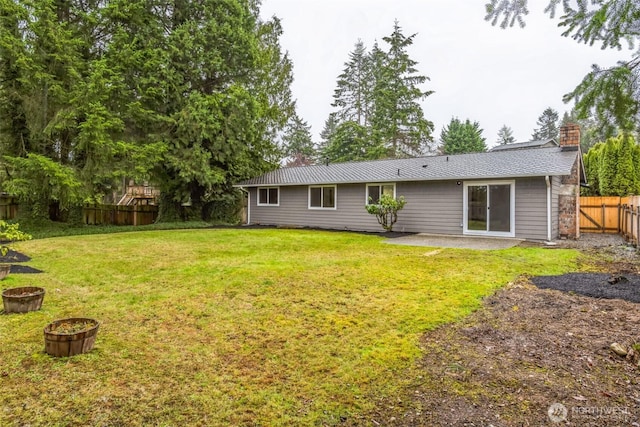 rear view of property with a lawn, a chimney, and a fenced backyard