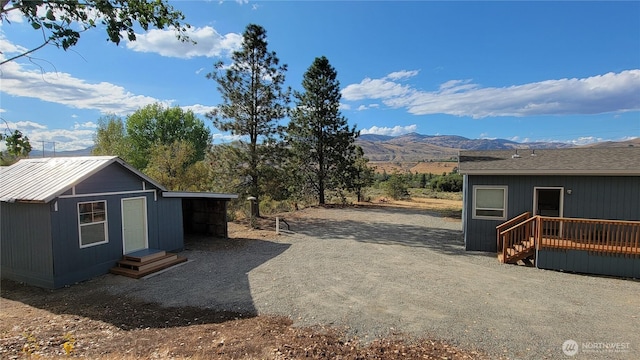 view of yard featuring entry steps, an outbuilding, a mountain view, and dirt driveway