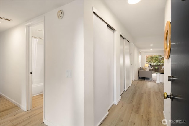 hall with light wood-style flooring, recessed lighting, baseboards, and visible vents