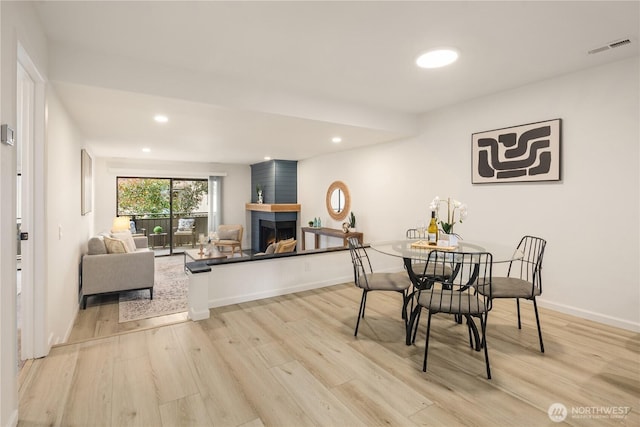 dining space featuring recessed lighting, a fireplace, visible vents, and light wood finished floors