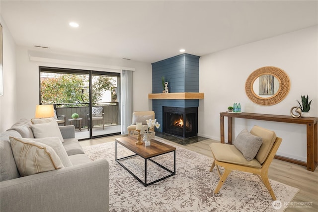 living area featuring recessed lighting, light wood-style floors, and a multi sided fireplace