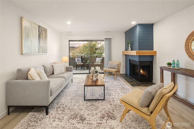 living area with recessed lighting, baseboards, wood finished floors, and a fireplace