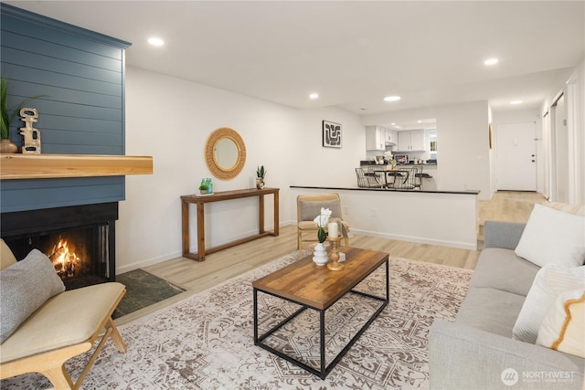 living area featuring a large fireplace, recessed lighting, and light wood-type flooring