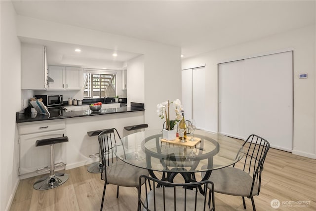 dining space with light wood finished floors, recessed lighting, and baseboards