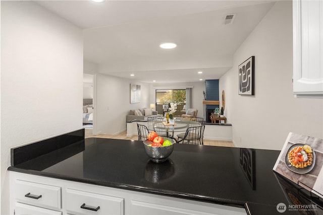 kitchen with dark countertops, open floor plan, recessed lighting, and white cabinetry