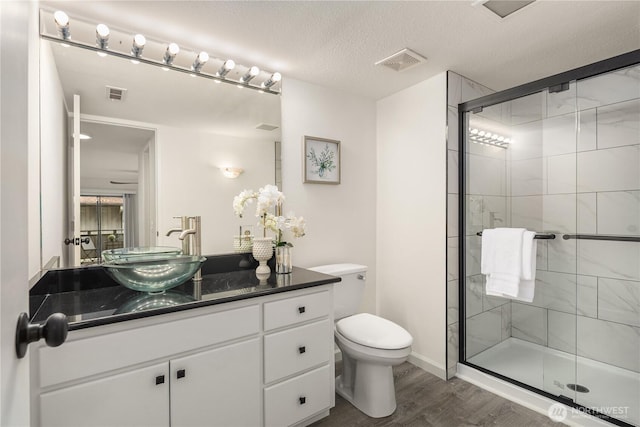 full bathroom featuring visible vents, wood finished floors, toilet, and a stall shower