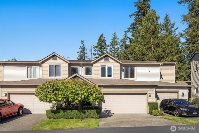 view of property featuring driveway, an attached garage, and a shingled roof