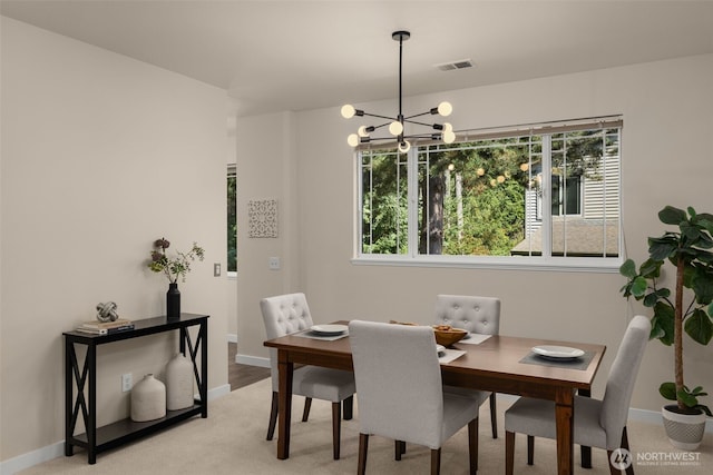 dining room featuring a notable chandelier, visible vents, light colored carpet, and baseboards