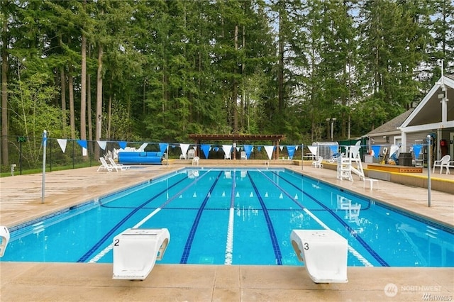 community pool featuring a patio area, fence, and a diving board