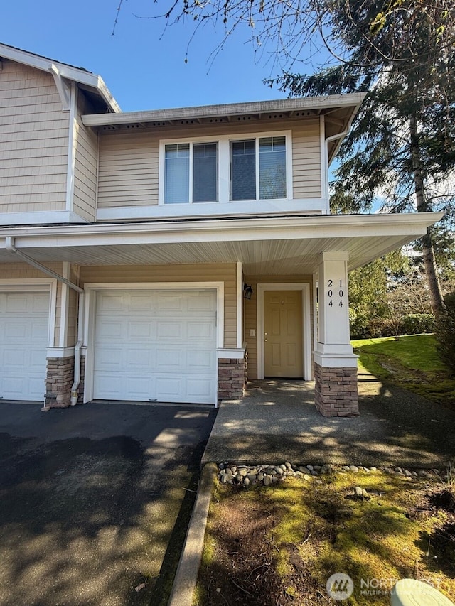 view of front facade with aphalt driveway, stone siding, and a garage