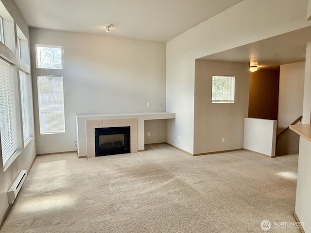 unfurnished living room with a baseboard radiator, carpet floors, baseboards, and a tiled fireplace