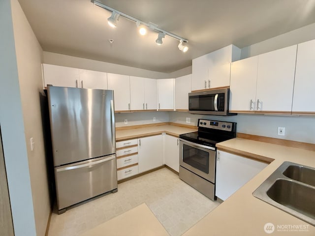 kitchen featuring light countertops, white cabinets, appliances with stainless steel finishes, and a sink