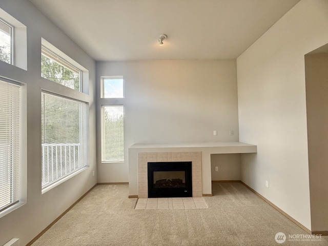 unfurnished living room featuring baseboards, carpet floors, and a fireplace