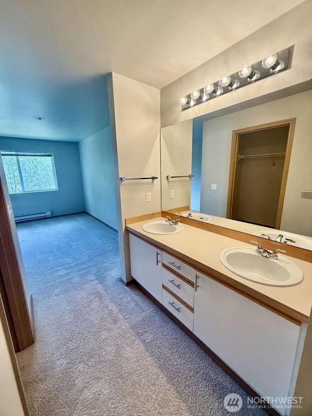 full bath with double vanity, carpet flooring, a baseboard radiator, and a sink