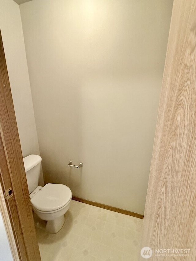 bathroom with baseboards and toilet