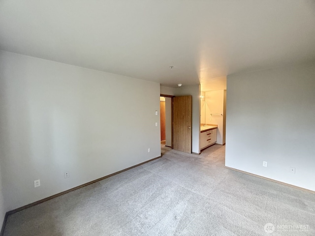 unfurnished room with baseboards and light colored carpet