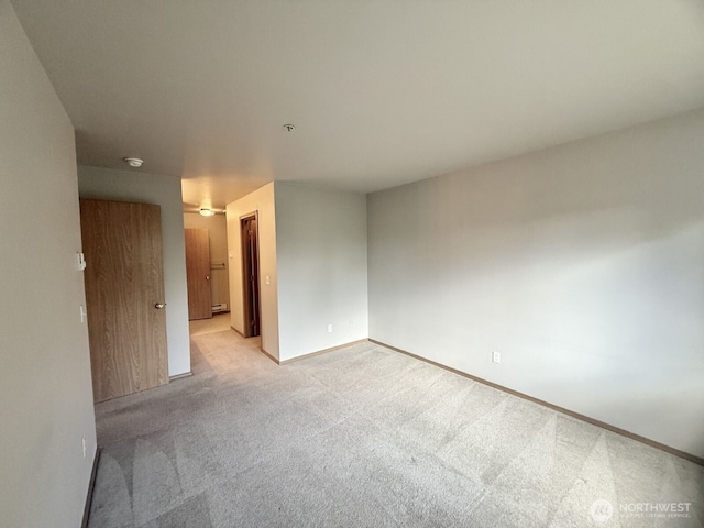 empty room featuring light colored carpet, baseboards, and baseboard heating