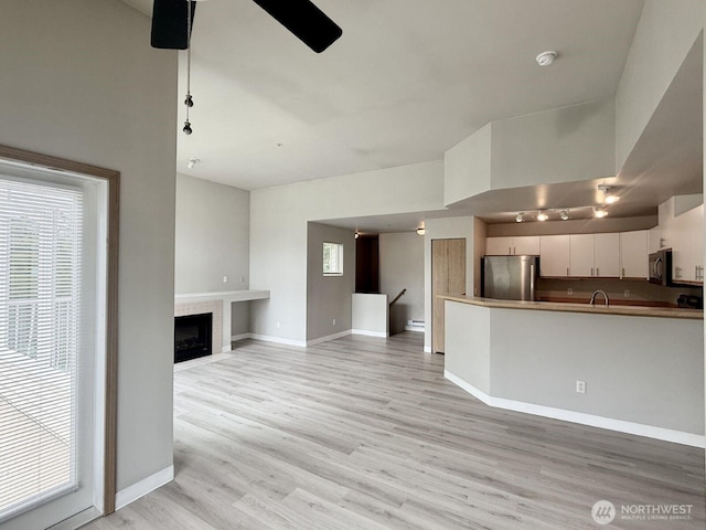 22212 42nd Ave S Unit 204, Kent, WA 98032 - unfurnished living room with healthy amount of natural light, light wood-type flooring, a tile fireplace, and rail lighting