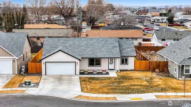 view of front of house with fence, driveway, roof with shingles, an attached garage, and a residential view