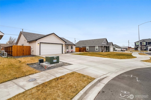 ranch-style house featuring fence, concrete driveway, roof with shingles, a front yard, and a garage