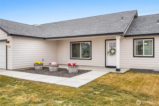 view of front facade featuring an attached garage, a front yard, and a shingled roof