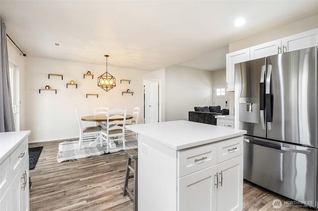 kitchen featuring light countertops, white cabinets, stainless steel fridge, and light wood-type flooring