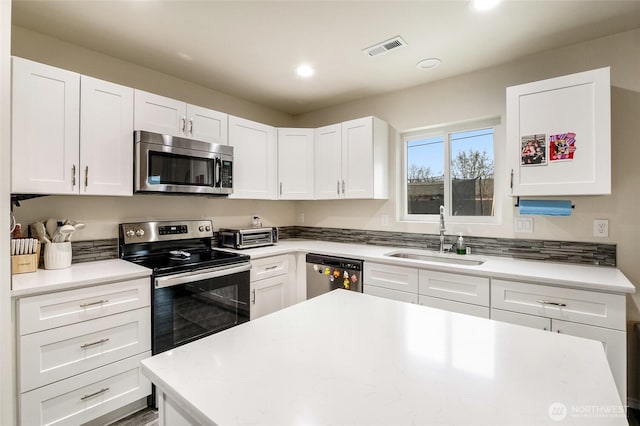 kitchen featuring visible vents, light countertops, appliances with stainless steel finishes, white cabinetry, and a sink