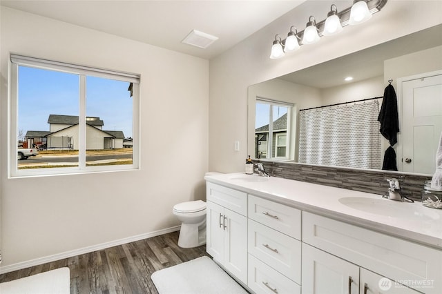 bathroom featuring toilet, wood finished floors, baseboards, and a sink