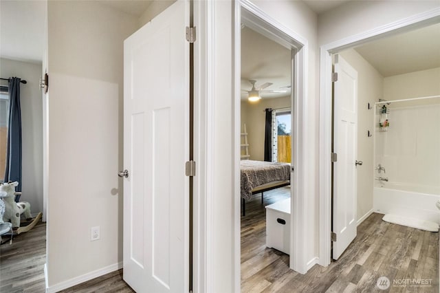 corridor featuring baseboards and wood finished floors