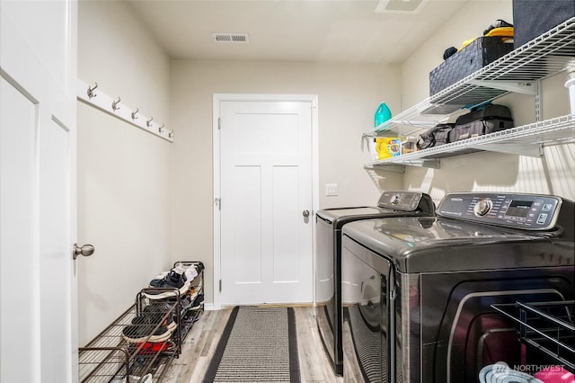 laundry area featuring laundry area, wood finished floors, visible vents, and independent washer and dryer