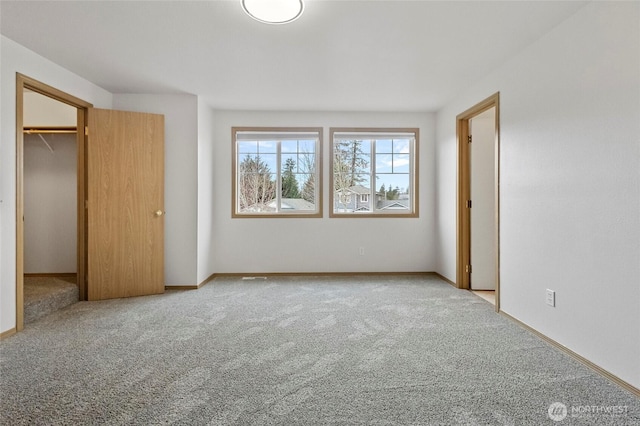 unfurnished bedroom featuring a spacious closet, baseboards, and carpet floors