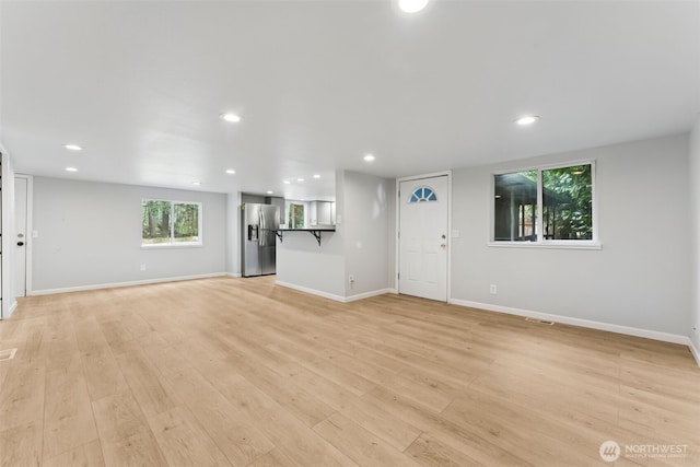 unfurnished living room with recessed lighting, light wood-type flooring, and baseboards