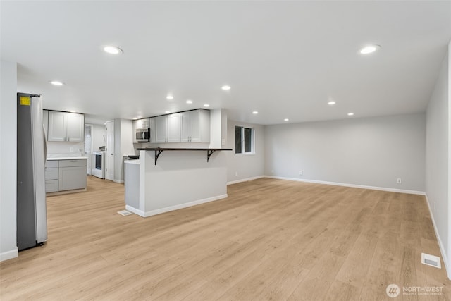 unfurnished living room with recessed lighting, visible vents, washer / dryer, and light wood finished floors