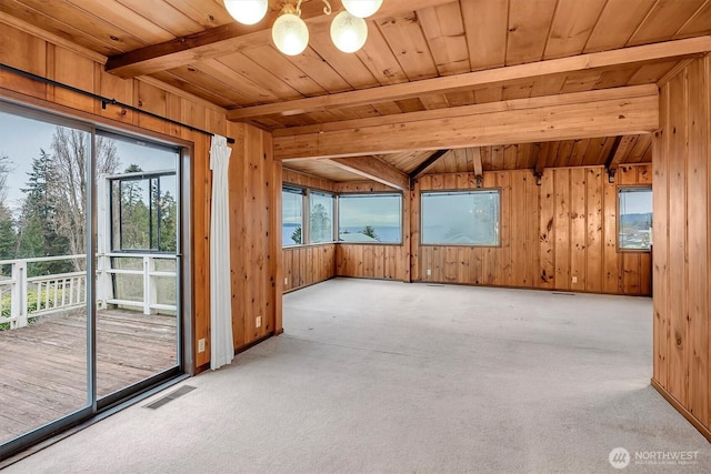 carpeted spare room featuring wooden ceiling, lofted ceiling with beams, visible vents, and wood walls